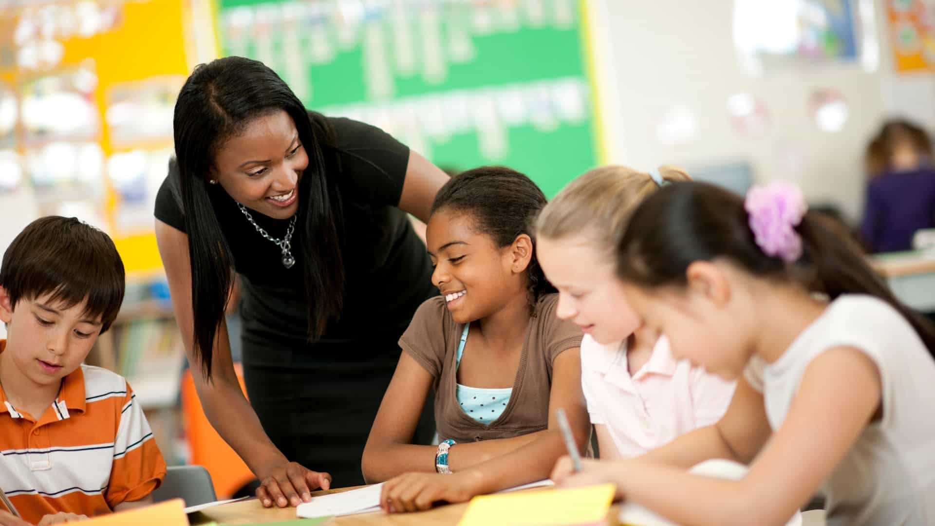 Teacher helping students in a classroom while building her teaching career